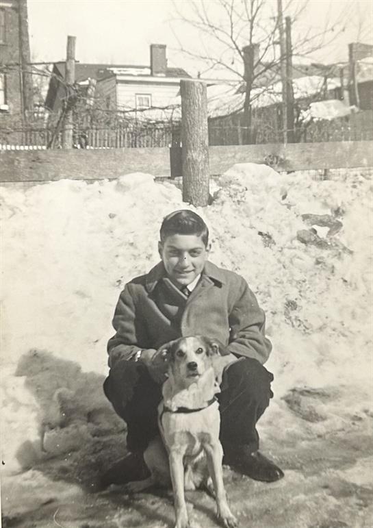 A boy kneeling with a dog in the snow