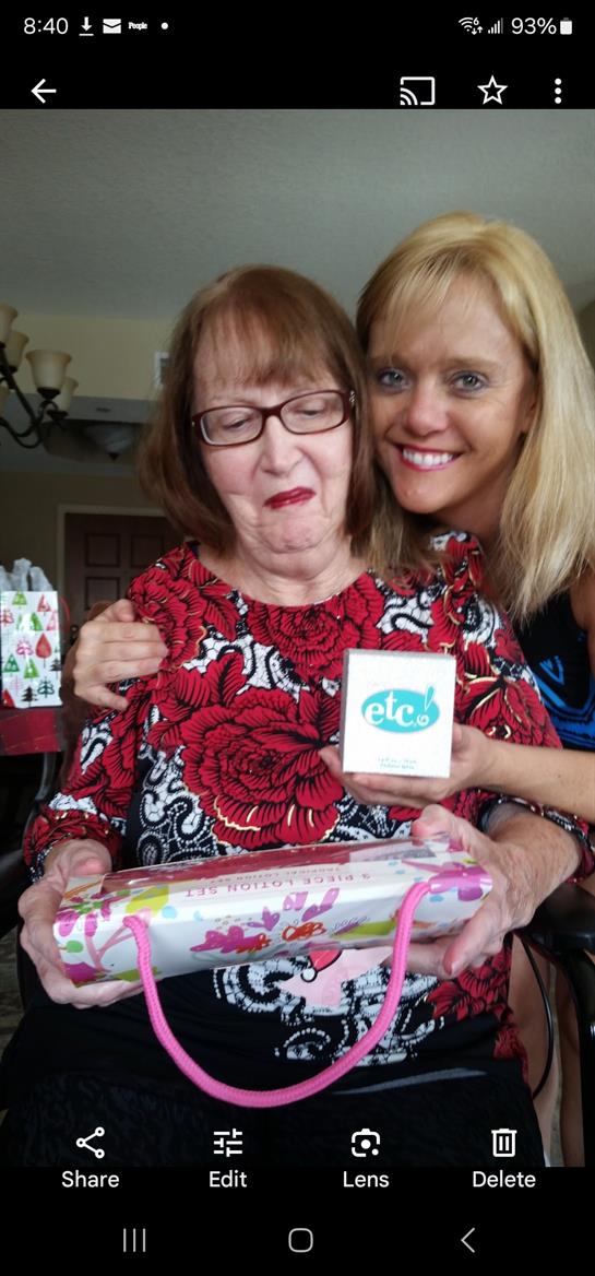 A joyful woman presents a gift to her grandmother during a family celebration at home.