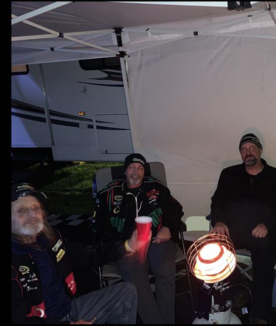 Friends enjoy a cozy evening under a canopy, warming up with conversation and cups.