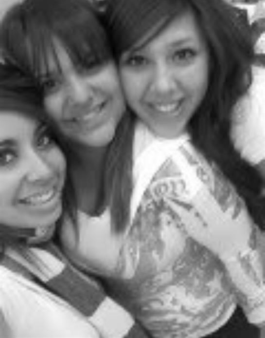 Three friends smile and embrace each other while celebrating at a lively indoor event.