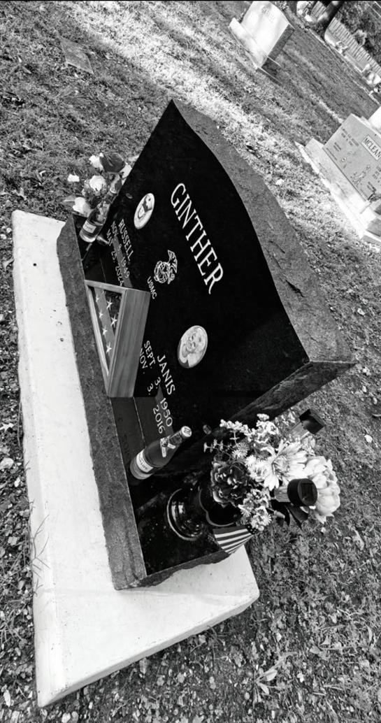 A grave stone with flowers and a flag