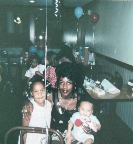 A joyful gathering with children interacting and a woman holding a baby in a restaurant setting.