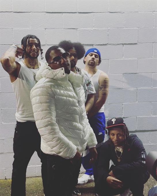 Five friends pose confidently outdoors in dim light, showcasing their casual style.