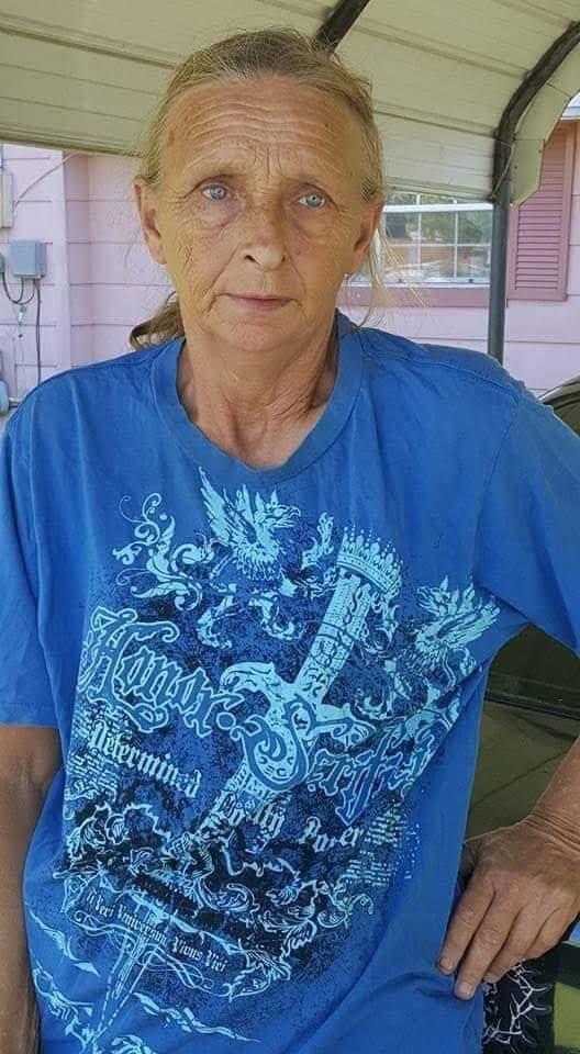 A person wearing a blue shirt poses confidently next to a car in a home setting.