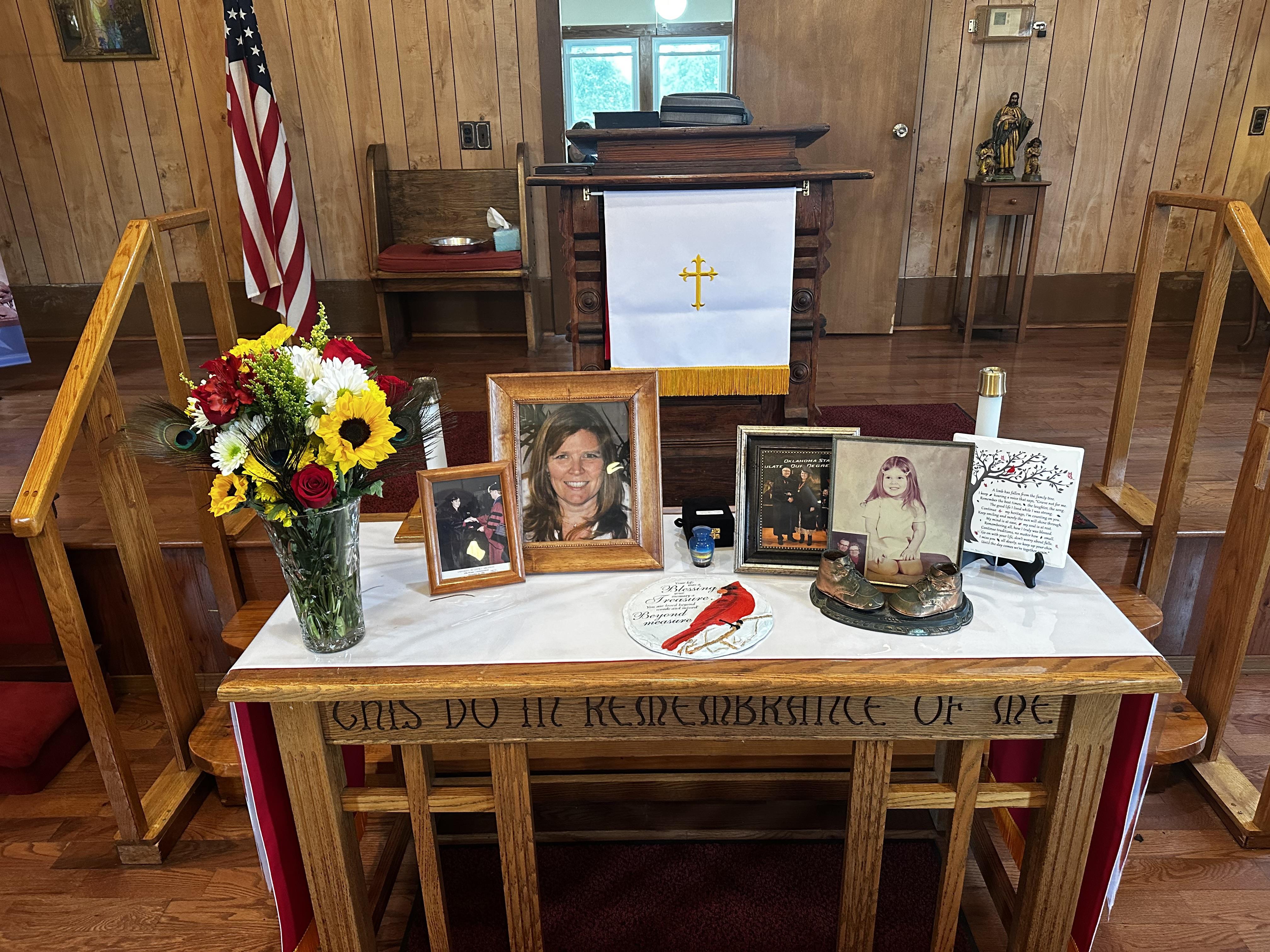A touching memorial with flowers, photos, and candles in a rustic church.
