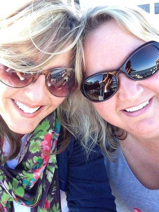 Two friends smile brightly while enjoying their day at the beach, wearing stylish sunglasses.