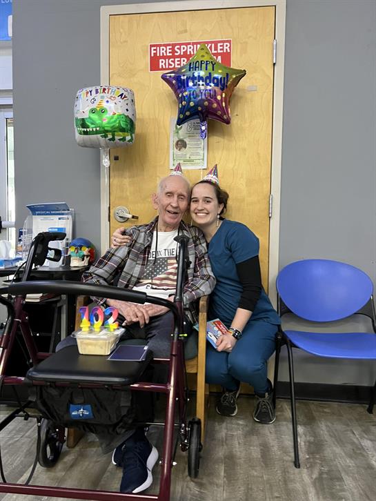 A man in a wheelchair with a woman in a birthday hat