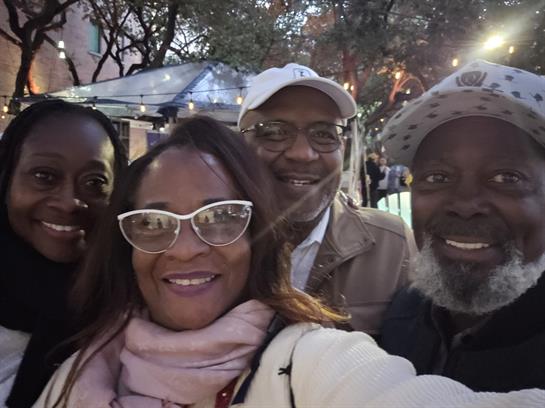 Group of friends smiling and posing for a cheerful selfie in a vibrant outdoor setting.
