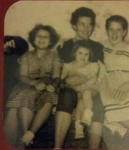 A group of four women and a girl pose together, smiling warmly in a relaxed atmosphere.