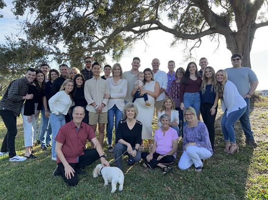 Large group enjoying a joyful family reunion in a beautiful outdoor setting under a tree.