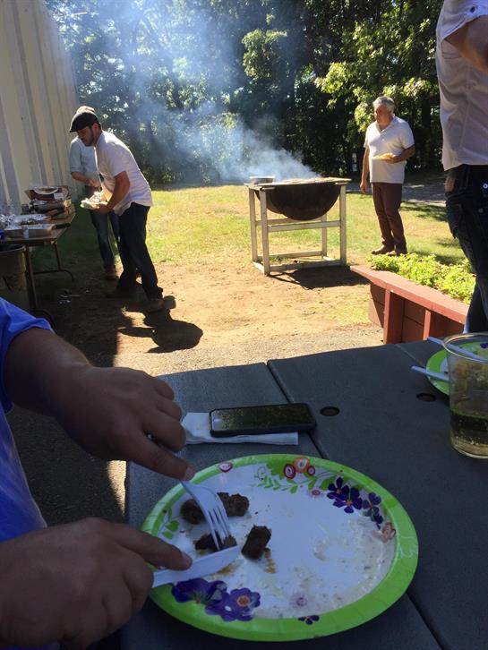 Friends enjoy a barbecue, cooking meat and savoring food in a beautiful outdoor garden.