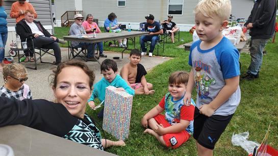 A group of children and adults share laughter and fun during an outdoor gathering in the park.