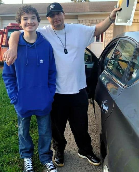 A man and boy standing next to a car
