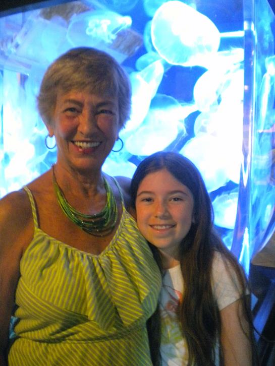 Two happy family members embrace in front of a vibrant jellyfish exhibit together.