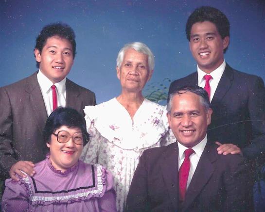 A family of five poses together with warm smiles, dressed in formal outfits.