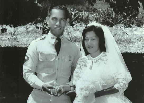 Newlyweds pose joyfully in a garden, surrounded by greenery, on their special day.