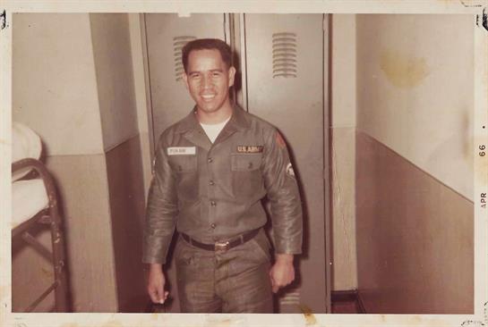 A young soldier stands proudly in military attire inside a barracks, capturing the era's spirit.