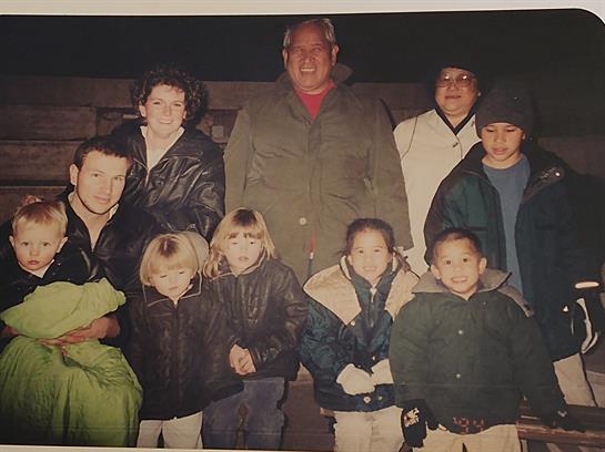 A joyful gathering of children and adults smiles for a group picture in a cool evening.