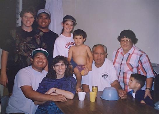 A group of adults and kids share smiles and laughter together at a table.