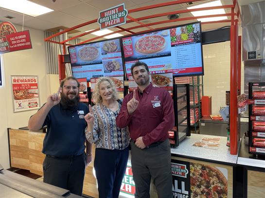 Staff members happily pose after a successful restaurant grand opening event in the afternoon.