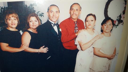 A group of six adults poses together, dressed elegantly for a festive family celebration.