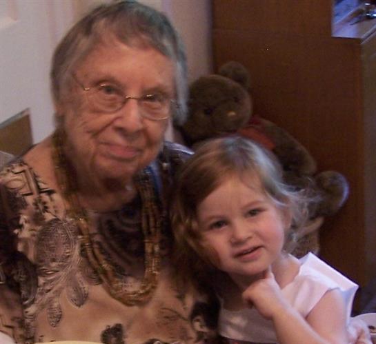 A young girl poses with her grandmother, sharing a quiet moment of joy and connection indoors.