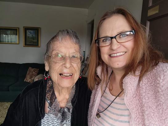 Two women share a joyful moment, smiling brightly in a warm, inviting living room.