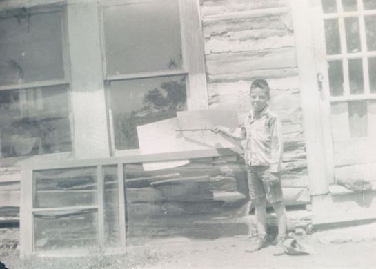A boy standing in front of a house