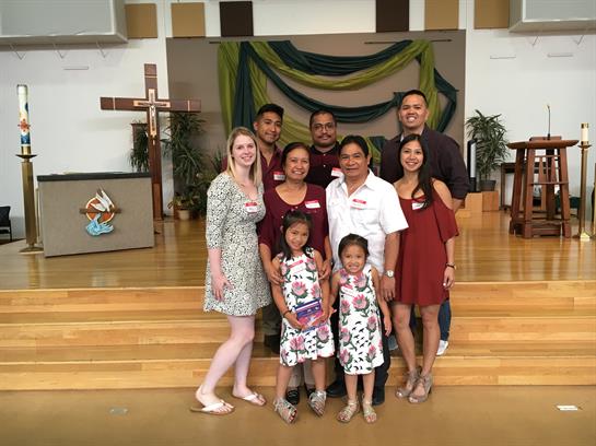 A diverse family group poses happily inside a community center, showcasing unity and joy.
