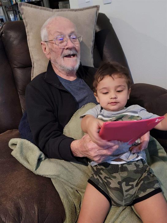 An old man and a young boy sitting on a chair