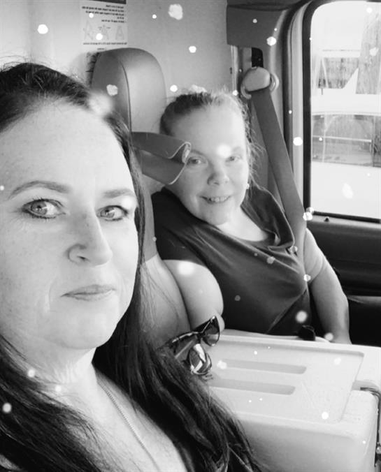 Two women enjoy each other's company inside a car, smiling while parked in a lively area.