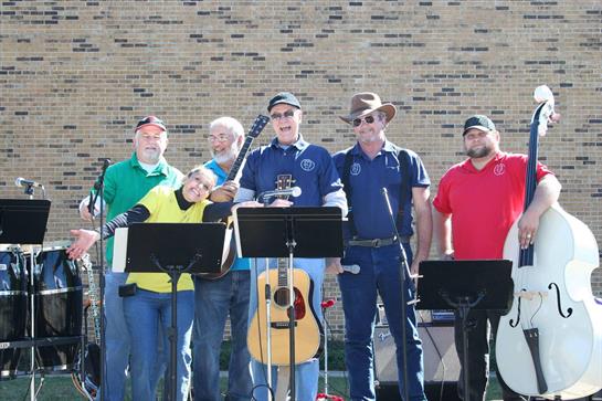 A group of musicians plays a vibrant set, entertaining a crowd in an outdoor setting.