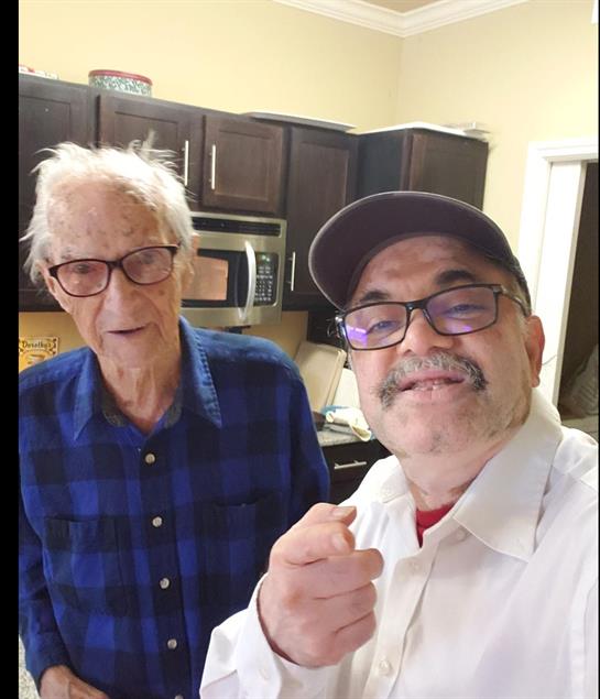 Two men smile happily in a kitchen, celebrating together with a joyful moment captured.