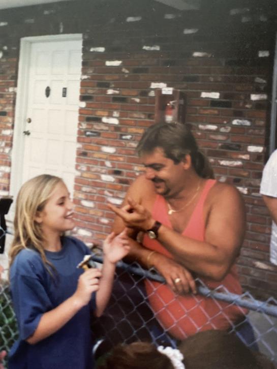 A man and a girl standing next to a fence