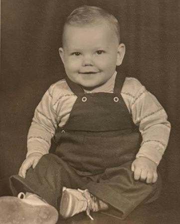 A baby in overalls smiling