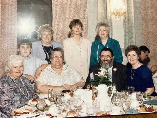 Eight family members enjoy a meal together at a table filled with dishes and drinks.