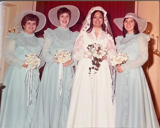 Four bridesmaids in matching dresses pose with the bride at a wedding ceremony.