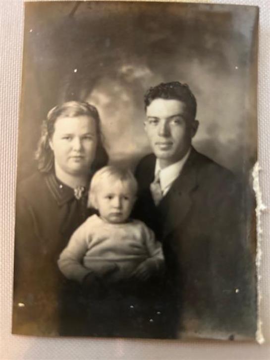 A mother and father pose proudly with their young child captured in a vintage style.