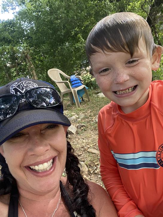 Two people are smiling joyfully together outdoors on a sunny day.
