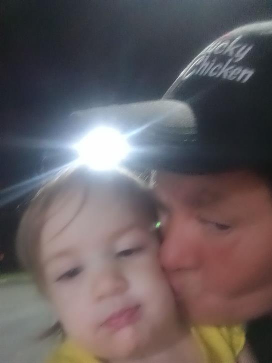 A father shares a tender moment with his child while enjoying nighttime outdoor activities.