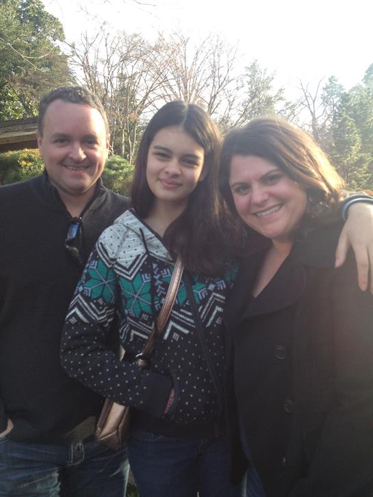 Family poses happily together outdoors, capturing a moment of joy during a sunny day.