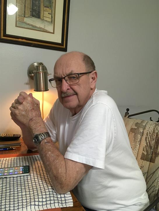 An older man sits thoughtfully at a table, enveloped in a warm, inviting atmosphere.