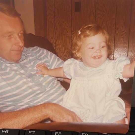 A young girl joyfully interacts with a man while sitting on a comfortable couch.