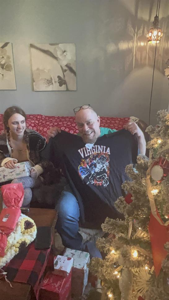 Family members enjoy gift exchange near a decorated Christmas tree in a cozy living room.