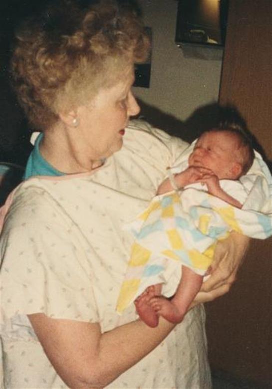 A loving grandmother gently cradles her newborn grandchild in a cozy, home setting.
