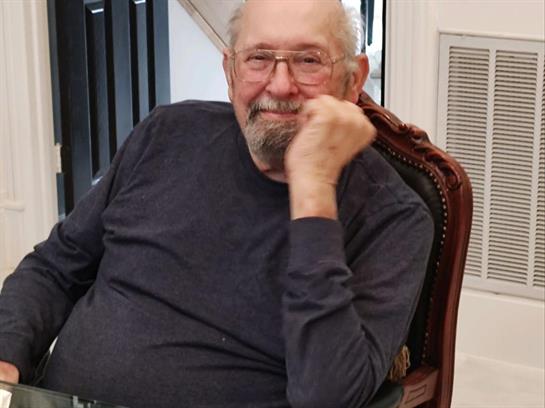 A cheerful elderly man enjoys a moment of relaxation in a cozy indoor setting.