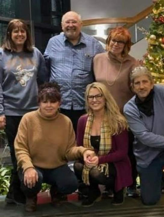 Friends smiling together in a festive atmosphere, surrounded by holiday decorations.