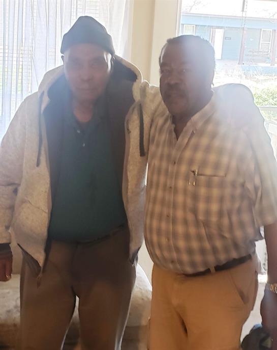 Two men are standing closely together, smiling happily as they enjoy their time indoors.