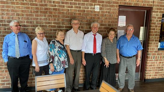 A group of elderly individuals enjoys a joyful reunion at a local community hall.