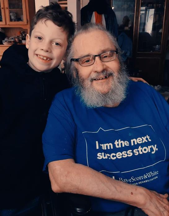 A smiling boy poses closely with his grandfather, highlighting their loving bond in a cozy setting.